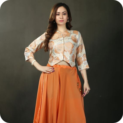 Woman wearing saffron-cream crop top with a saffron dhoti-style skirt