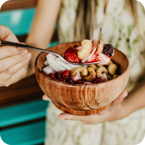 woman showing nuts and berries in spoon