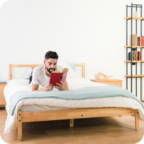 Man lying on bed and reading book